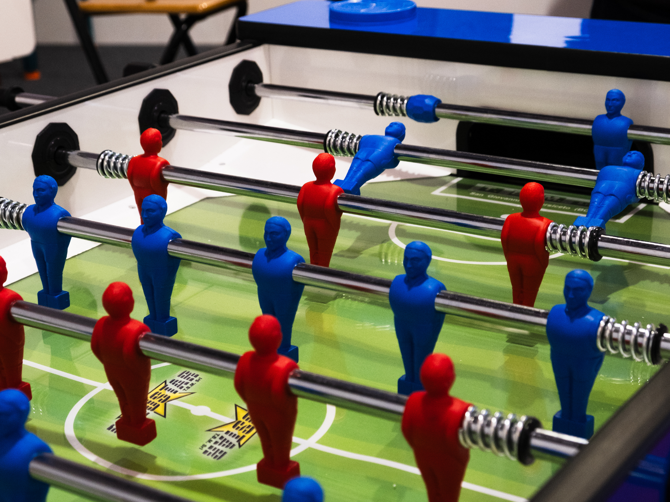 Dettaglio di un tavolo da calciobalilla, con giocatori rossi e blu